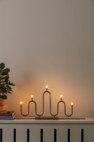 Noel 5 Messing Fra Globen Lighting - Det bl&oslash;de, b&oslash;lgede design er skabt af metalr&oslash;r, der er b&oslash;jet i h&aring;nden p&aring; forskellige niveauer, og giver en moderne fortolkning af den klassiske adventslysholder.