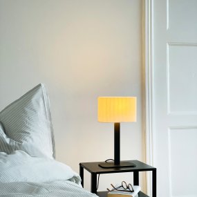 Calix oval 40cm Sort Fra Dyberg Larsen - Den ribbade, naturfärgade skärmen av textil medför en värme till rummet och i kombination med den svarta metallfoten passar Calix in i alla stilar och hem.