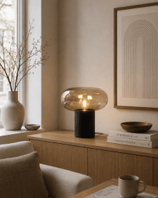 Alba 32cm Sort/ravgul bordlampe Fra Nordic Lighting - Den sorte metalbase giver et stabilt og elegant udtryk, mens den ravfarvede glassk&aelig;rm skaber et bl&oslash;dt og atmosf&aelig;risk lys.