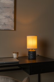Fran 30cm Sort bordlampe Fra Lucide - Det hvide, uregelmæssige mønster på foden giver et marmoreret udseende og skaber en flot kontrast mod den mørke overflade.