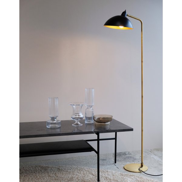 Futura Messing gulvlampe Fra Dyberg Larsen - Den sorte overflade og den antikfarvede inderside af sk&aelig;rmen spreder et varmt lys og skaber en hyggelig atmosf&aelig;re i hjemmet.