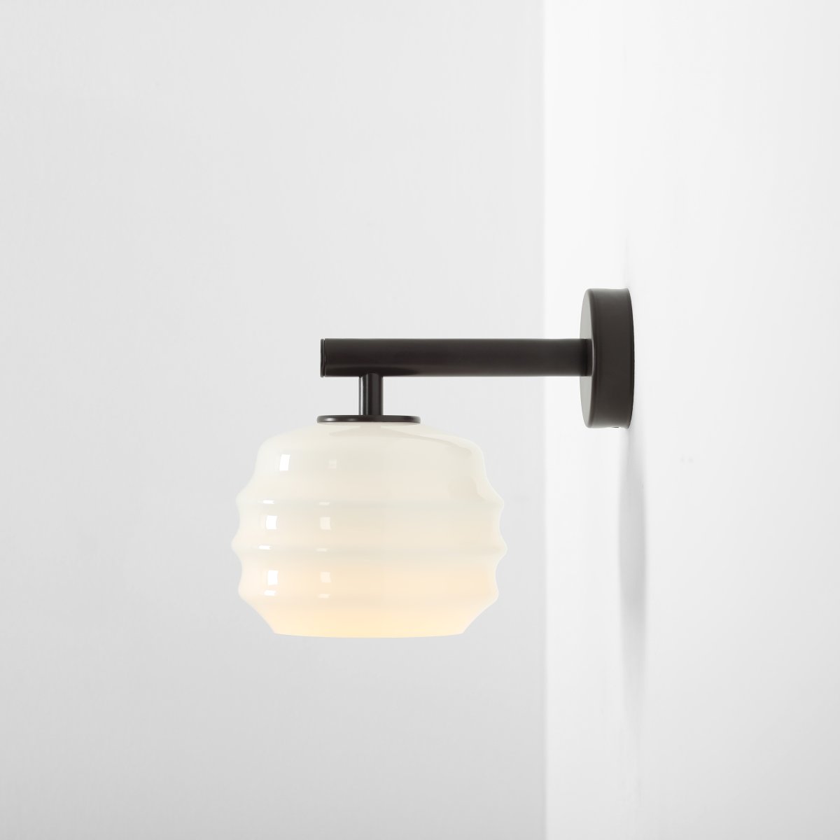 Puff 23cm Mørkebrun væglampe Fra Artera - Den dekorative skærm i hvidt opalglas har en bølget form, der giver lampen et legende og elegant udtryk.