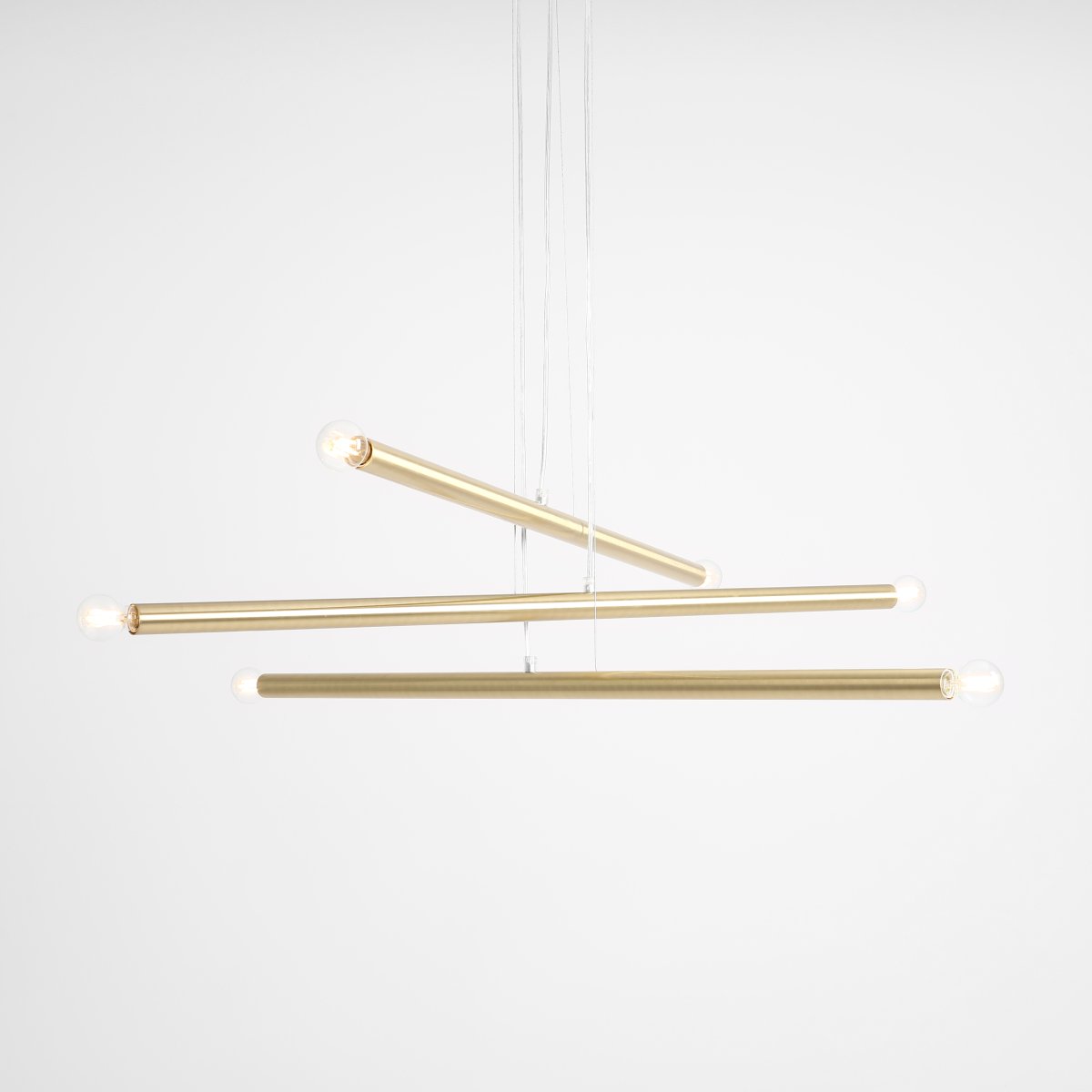 Tubo 6 100cm Messing loftslampe Fra Artera - Lampen består af tre smalle metalrør i en elegant messingfinish, placeret i forskellige højder og vinkler, der skaber et spændende og luftigt udtryk.