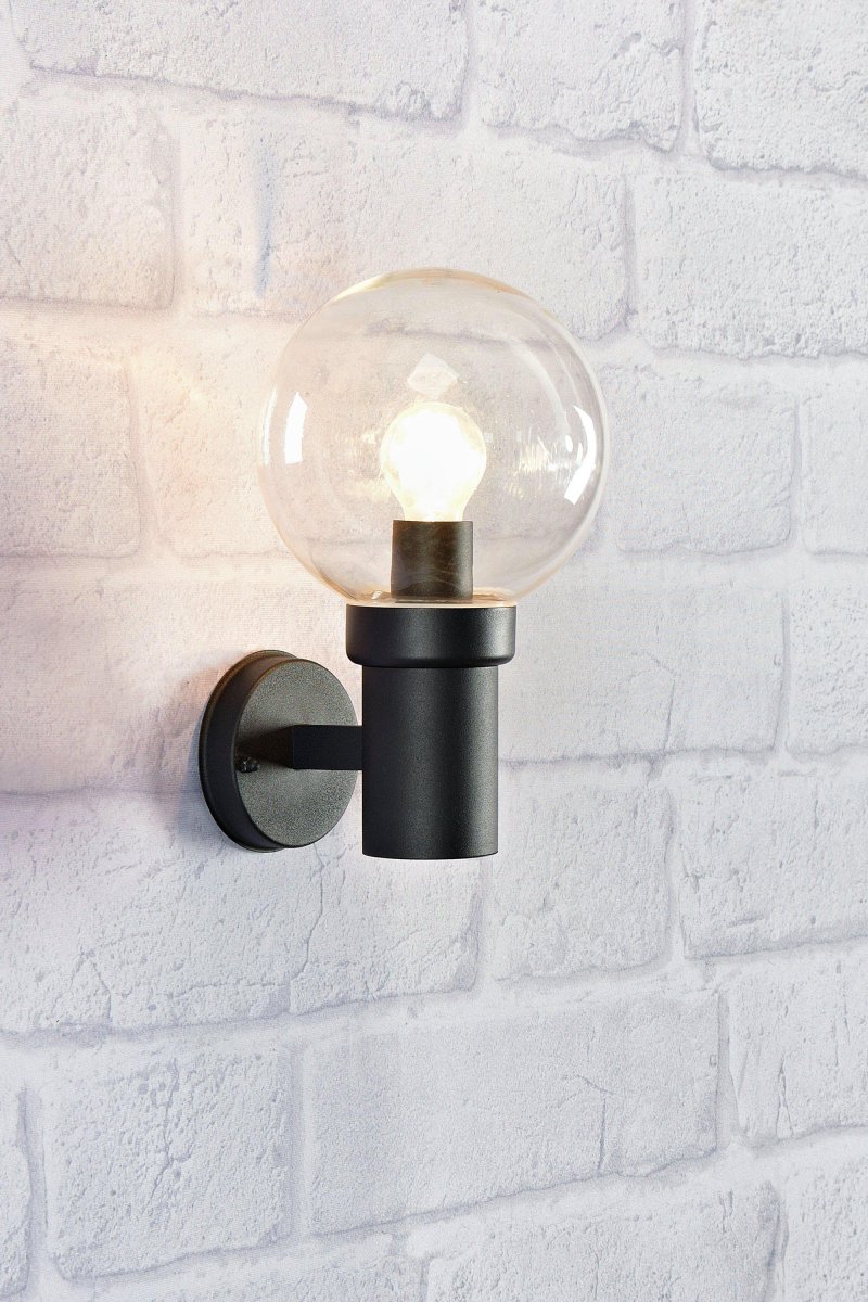 Caris Sort udendørslampe Fra Markslöjd - Med en robust, sort metalfod og en stor klar glaskuppel spreder lampen et klart og behageligt lys, der skaber en indbydende atmosf&aelig;re.