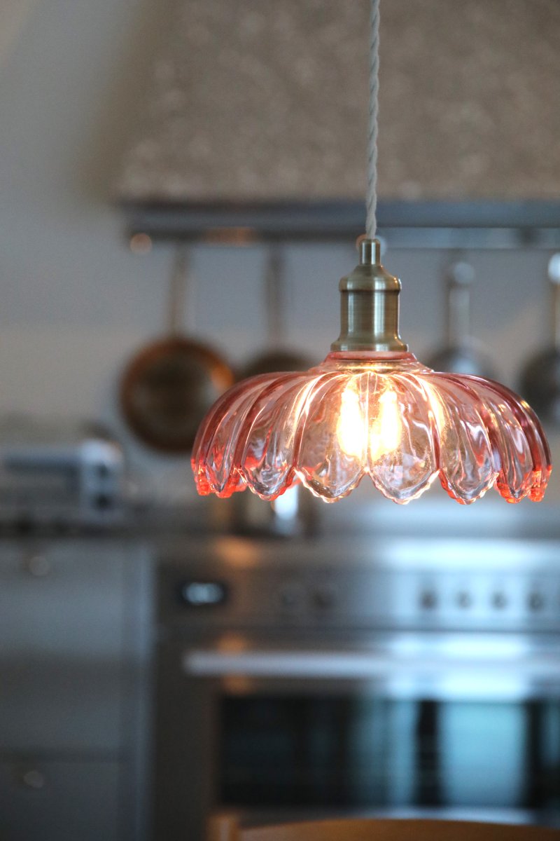 Kurage Ø26 Lyserød loftslampe Fra Markslöjd - Lampen har en lampeholder i messingfinish og en dekorativ beige snoet tekstilledning, der f&oslash;rer til en rund metalholder i samme messingfinish.