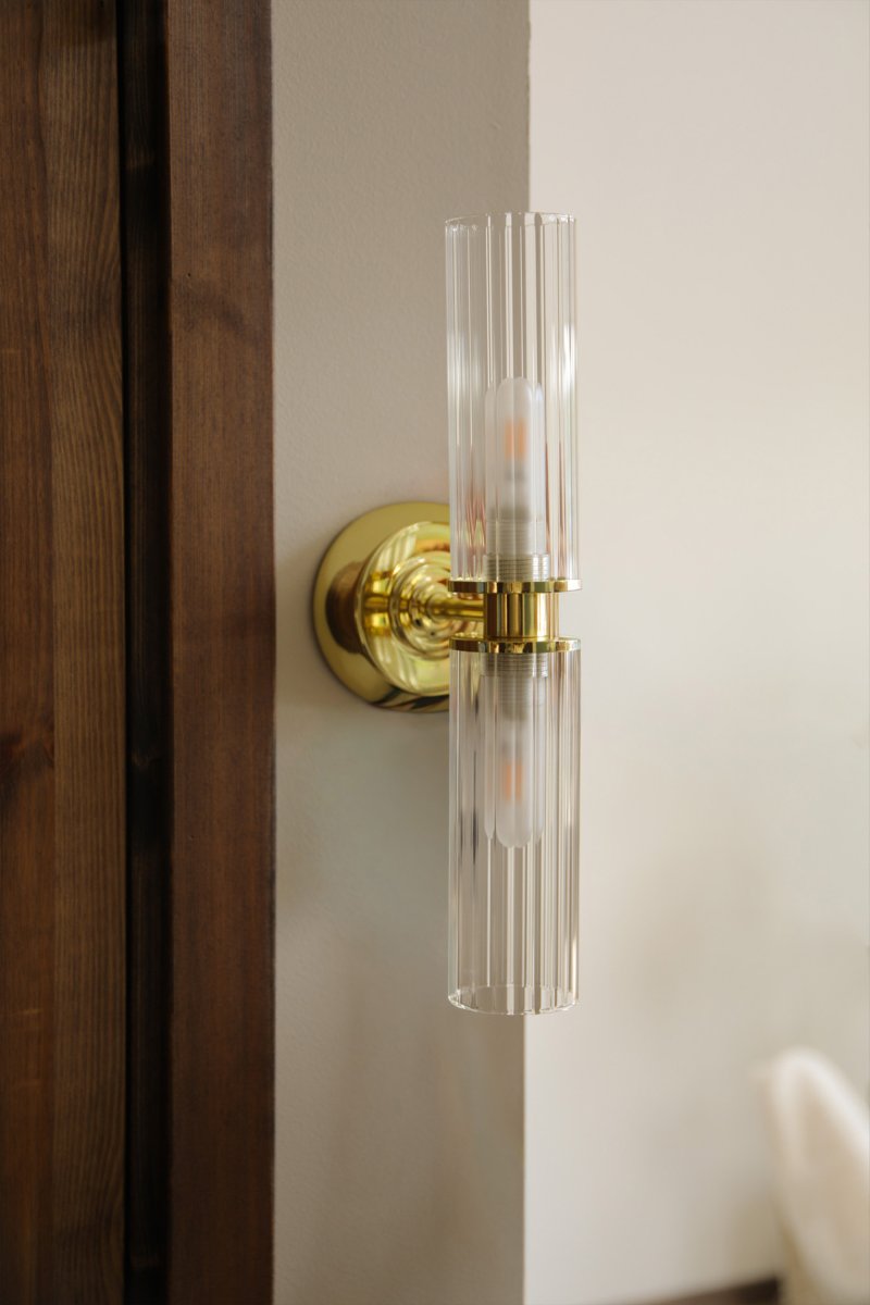 Rimini 35cm Messing badeværelseslampe Fra Markslöjd - Rimini er en elegant v&aelig;glampe med stilfulde detaljer i messingfinish og to aflange sk&aelig;rme i klart, riflet glas.