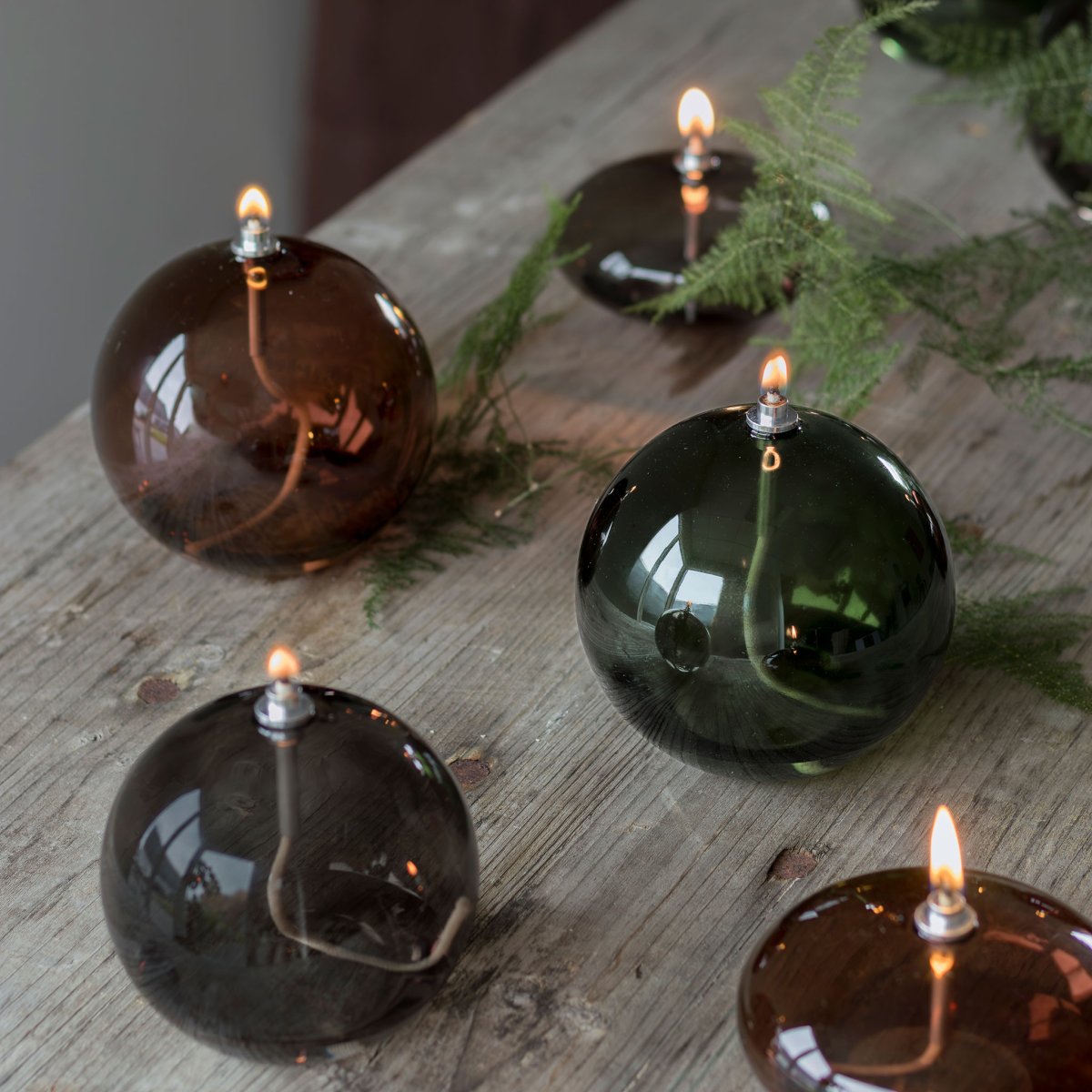 Oljelampa Aura Medium Røgfarvet Fra Mette Ditmer - Dess eleganta design och r&ouml;kf&auml;rgade glas sprider ett mjukt, varmt ljus som ger en lugn och mysig k&auml;nsla.