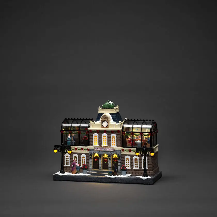 Mekanisk Juledekoration Med Togstation 25cm Flerfarvet Fra Konstsmide - Atmosf&aelig;risk togstation med bev&aelig;gelige figurer, 15 varmhvide LED-lys og indbygget julemusik, der bringer liv til din julelandsby.