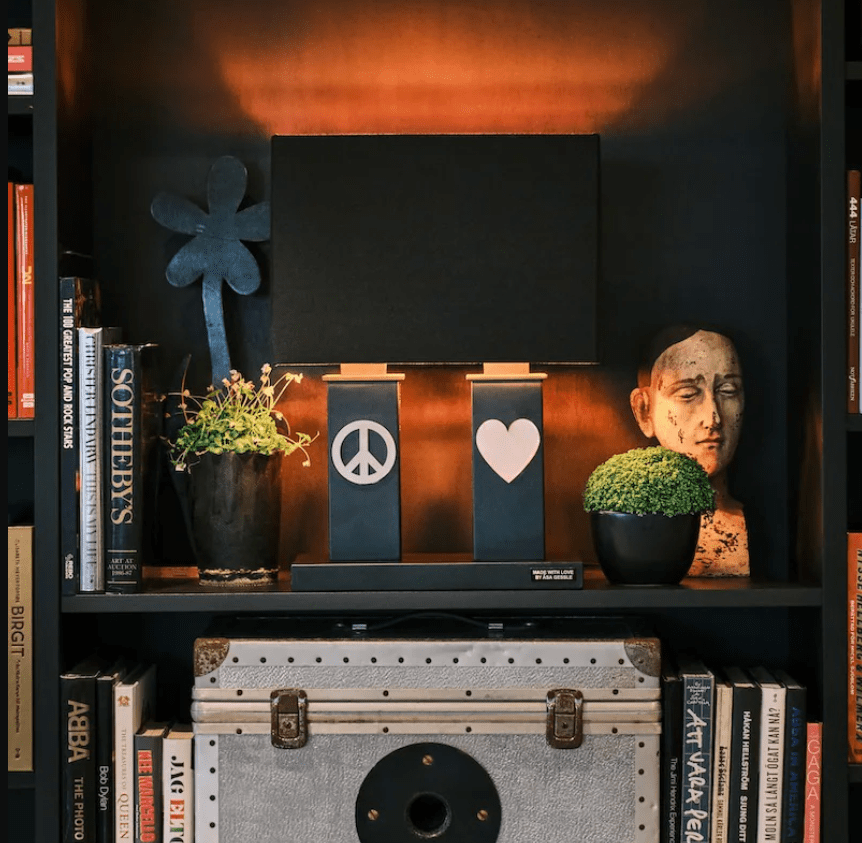 Stand By Me 50cm Sort bordlampe Fra By Rydéns - Den brede, sorte stoflampesk&aelig;rm harmonerer i kontrast til de smallere s&oslash;jler p&aring; lampefoden, som begge er dekoreret med et symbol i metal, fredstegn p&aring;; et og et hjerte p&aring; den anden.