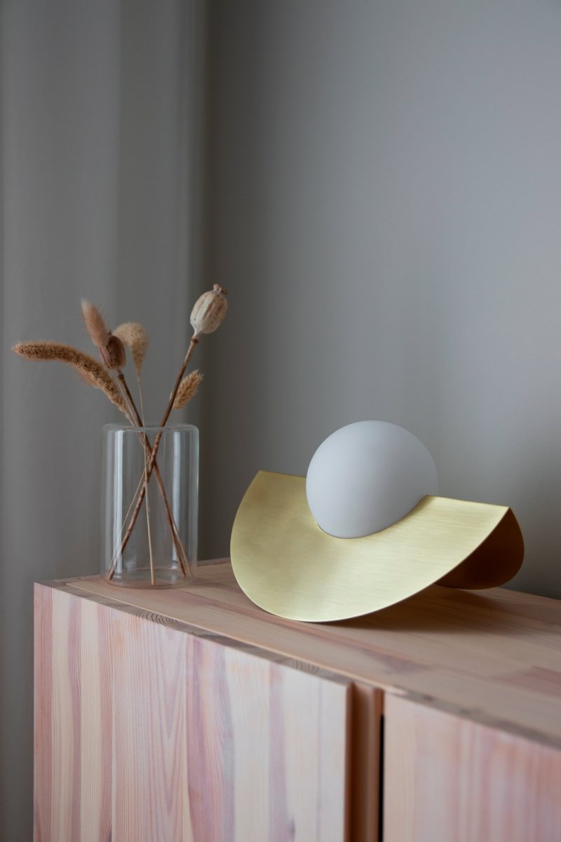 Roccia 17cm Børstet messing bordlampe Fra Globen Lighting - Den mat hvide glaskuppel hviler i et metalstativ, der er galvaniseret i børstet messing, som tilsammen danner et moderne og klassisk udtryk.