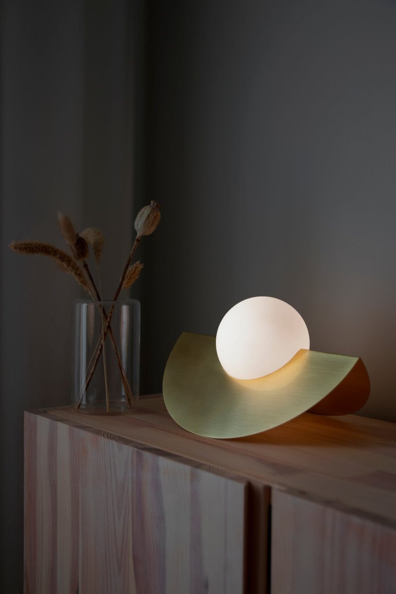 Roccia 17cm Børstet messing bordlampe Fra Globen Lighting - Den mat hvide glaskuppel hviler i et metalstativ, der er galvaniseret i børstet messing, som tilsammen danner et moderne og klassisk udtryk.