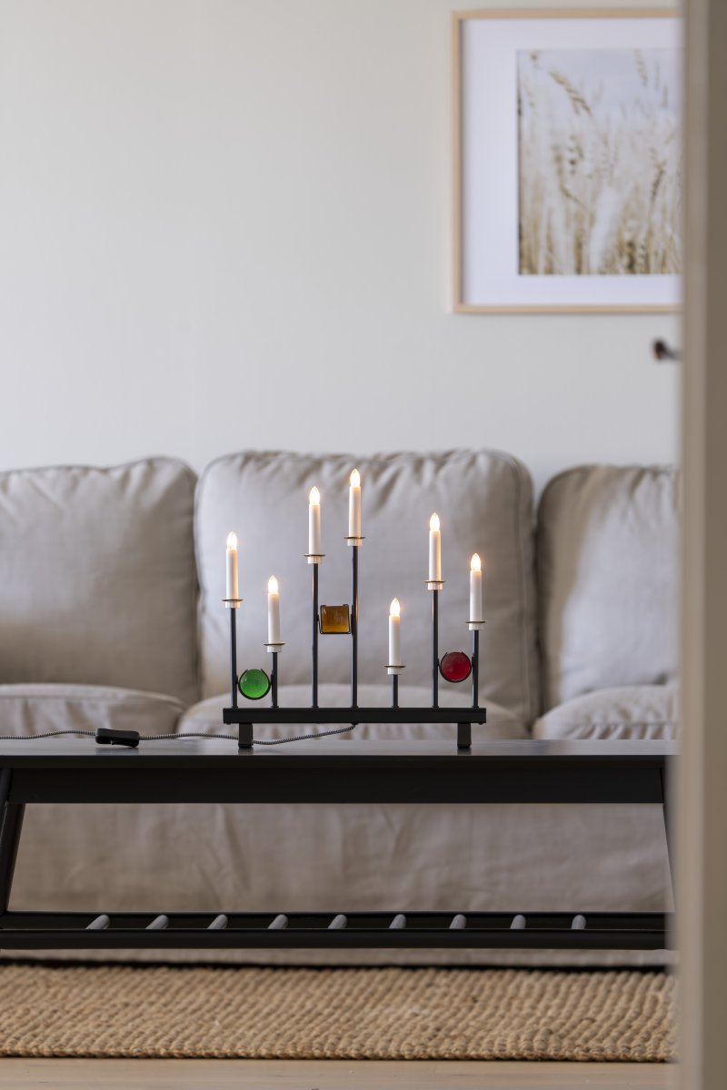 Candelabra 7 Lights Sort Fra Konstsmide - De syv lys er indrammet af dekorative farvede glasdetaljer i gr&oslash;n, r&oslash;d og rav, hvilket skaber en elegant og festlig atmosf&aelig;re.