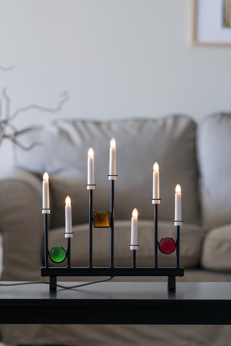 Candelabra 7 Lights Sort Fra Konstsmide - De syv lys er indrammet af dekorative farvede glasdetaljer i gr&oslash;n, r&oslash;d og rav, hvilket skaber en elegant og festlig atmosf&aelig;re.