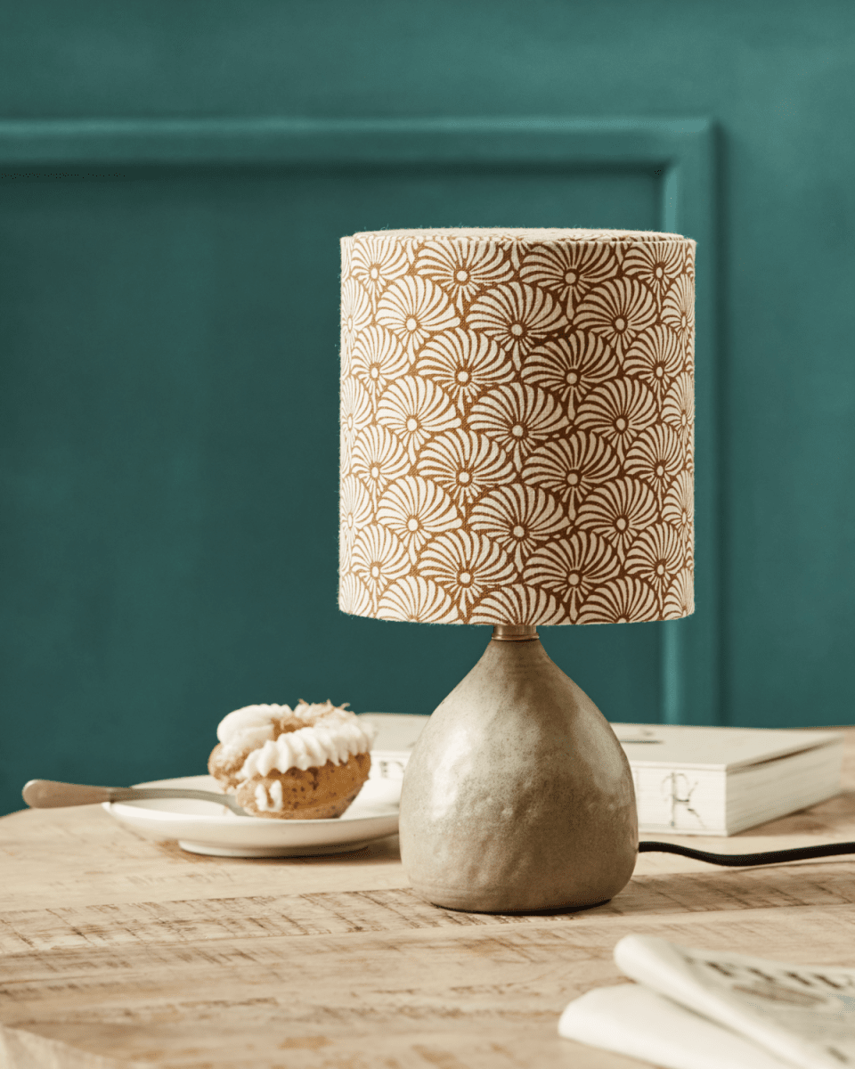 Flores 30cm Sand bordlampe Fra House Doctor - Den har en sandfarvet keramisk base og en hørlampeskærm prydet med håndtrykte sand- og brune viftemotiver, der smukt balancerer en moderne og hyggelig æstetik.