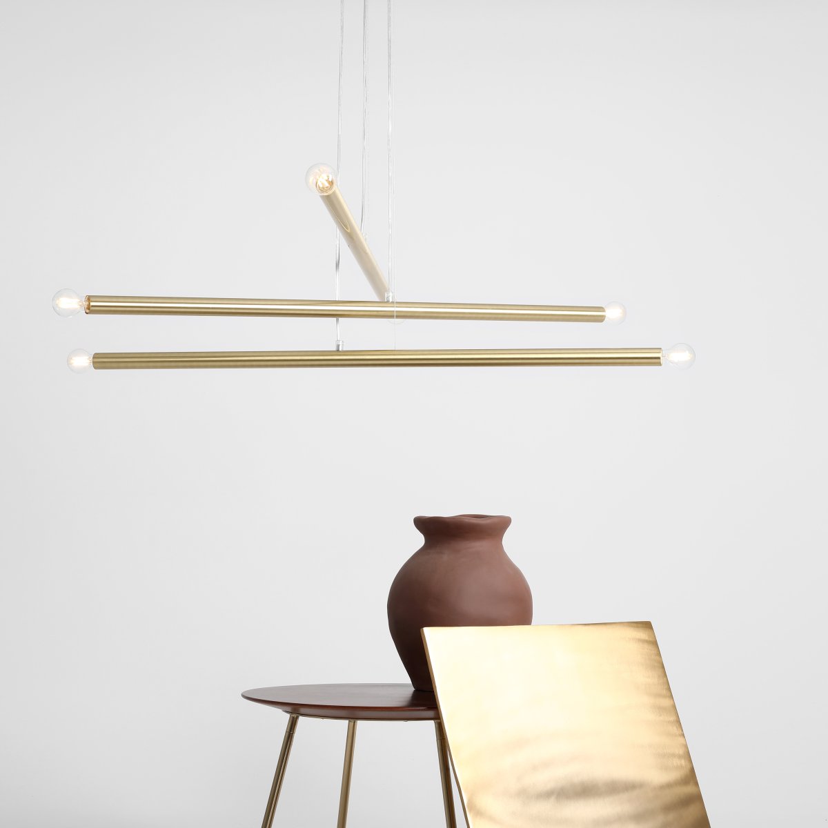 Tubo 6 100cm Messing loftslampe Fra Artera - Lampen består af tre smalle metalrør i en elegant messingfinish, placeret i forskellige højder og vinkler, der skaber et spændende og luftigt udtryk.