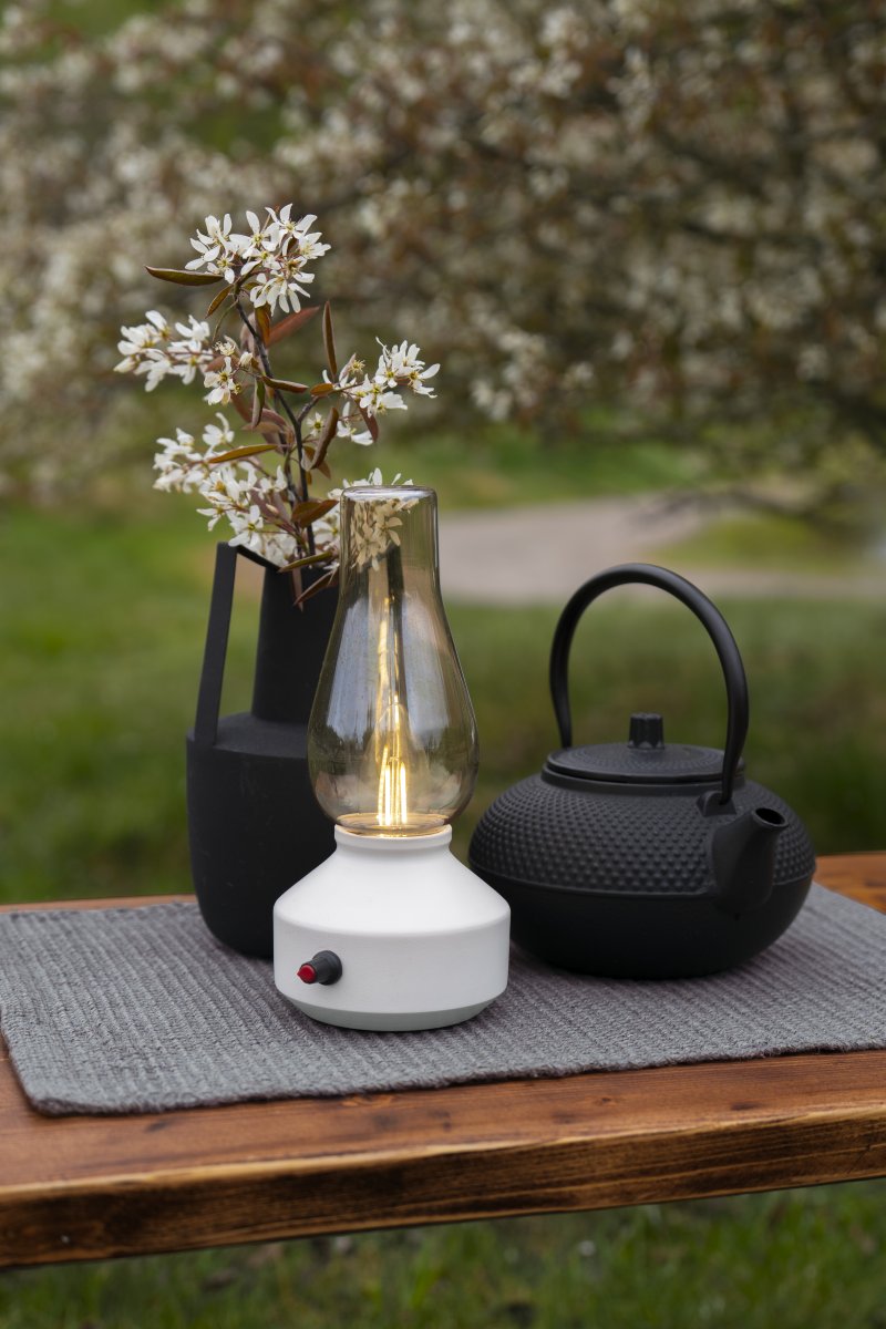 Genopladelig bordlampe 25cm Hvid bærbar Fra Konstsmide - Lampen er lavet af metal og glas med en hvid lampebase og en praktisk lysdæmper, der gør det nemt at justere det varme hvide, atmosfæriske lys.