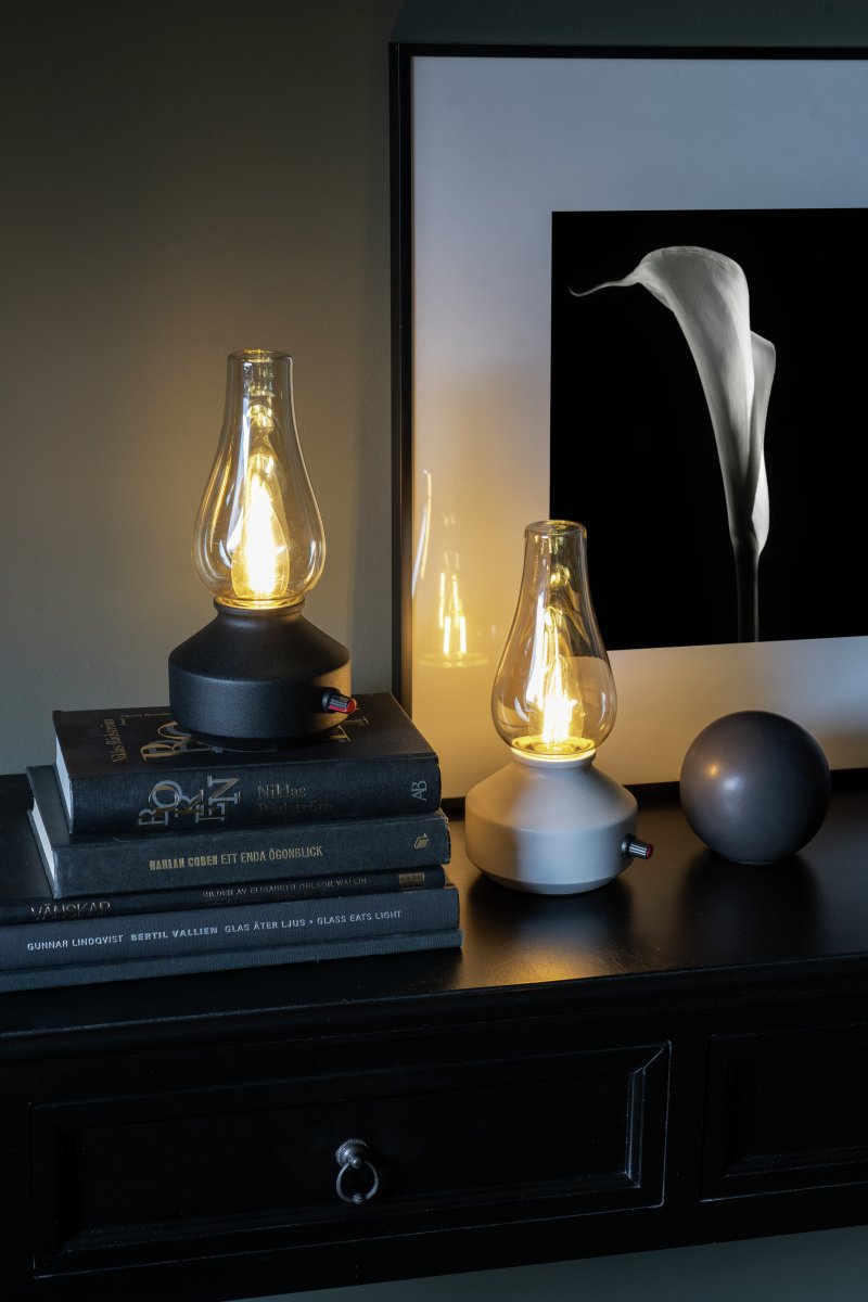 Genopladelig bordlampe 25cm Hvid bærbar Fra Konstsmide - Lampen er lavet af metal og glas med en hvid lampebase og en praktisk lysdæmper, der gør det nemt at justere det varme hvide, atmosfæriske lys.