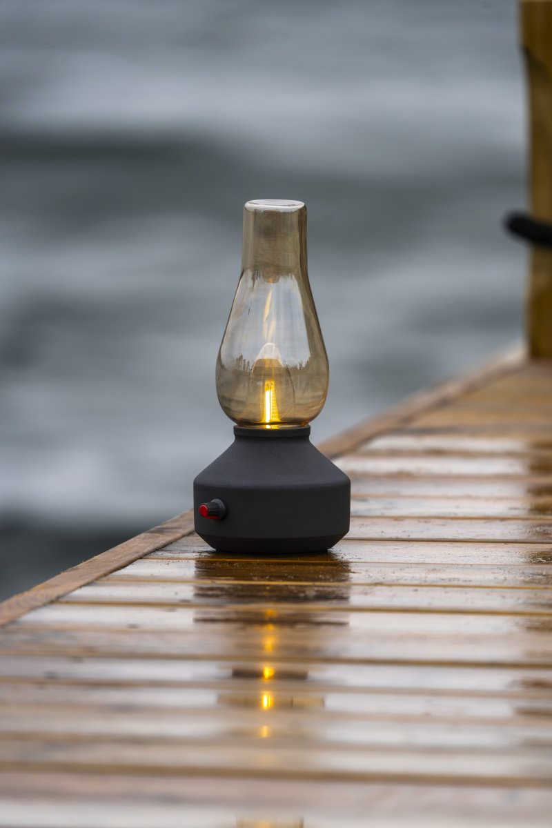 Genopladelig bordlampe 25cm Sort bærbar Fra Konstsmide - Lampen er lavet af metal og glas med en sort lampebase og en praktisk lysdæmper, der gør det nemt at justere det varme hvide, atmosfæriske lys.
