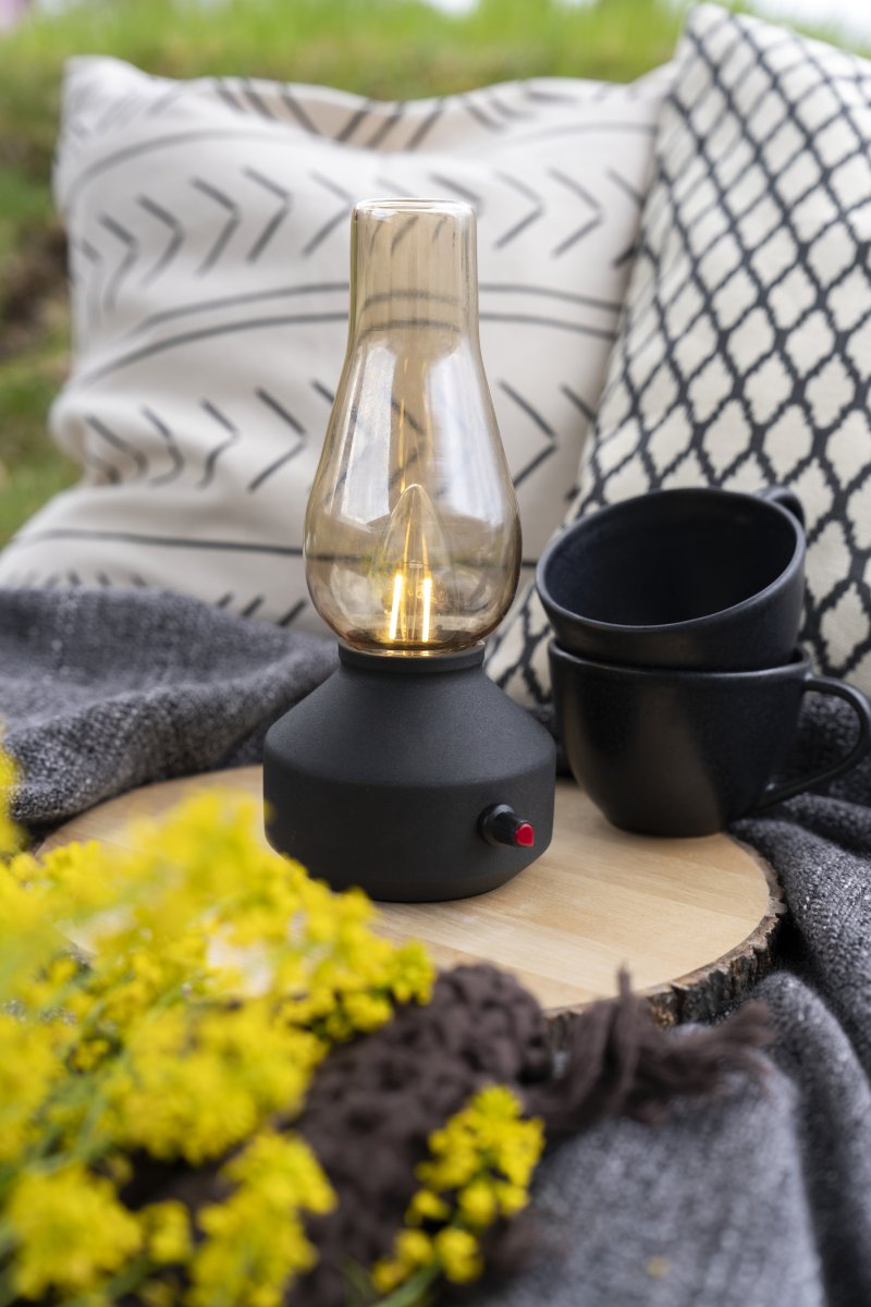 Genopladelig bordlampe 25cm Sort bærbar Fra Konstsmide - Lampen er lavet af metal og glas med en sort lampebase og en praktisk lysdæmper, der gør det nemt at justere det varme hvide, atmosfæriske lys.