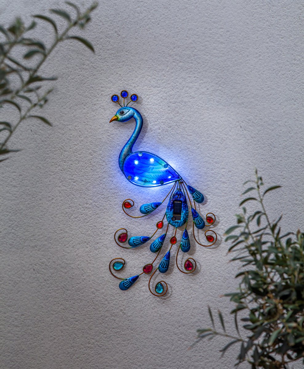 Peacock Multi-formål solcellelampe Fra Star Trading - Den er lavet af metal med smukke blå nuancer og bliver et iøjnefaldende element på vægge, hegn eller altaner.