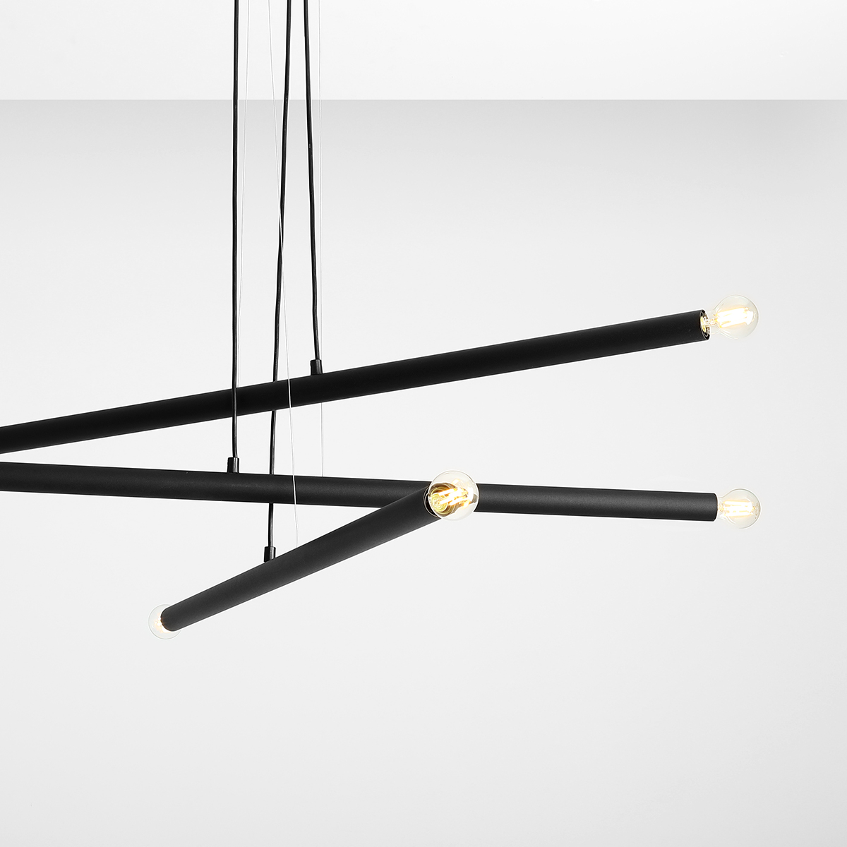 Tubo 6 100cm Sort loftslampe Fra Artera - Lampen består af tre smalle metalrør i en stilfuld sort finish, placeret i forskellige højder og vinkler, der skaber et spændende og luftigt udtryk.