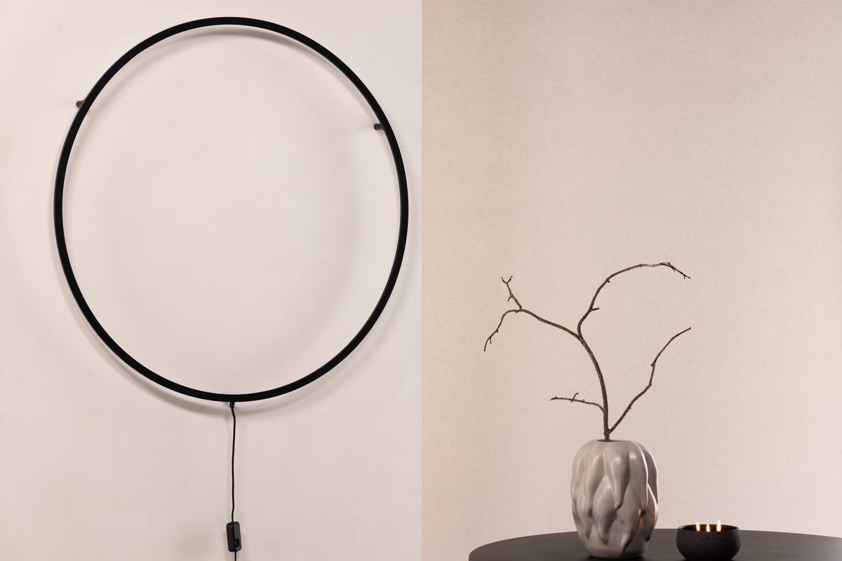 Sörmjöle Sort væglampe Fra Venture Design - Lampen har en rund ramme i sort aluminium med LED-lys bagved som giver et smukt lys på væggen og et behageligt skær i rummet.