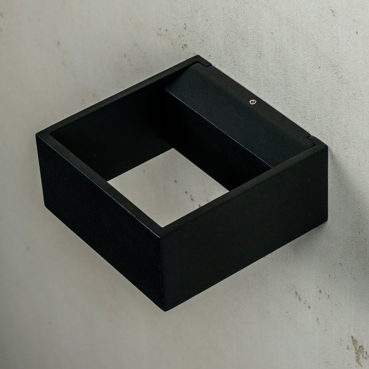 Jupiter Sort udendørslampe Fra Dyberg Larsen - Jupiter har en flad side mod væggen og en halvcirkelformet front med en LED lyskilde, der lyser op og ned langs væggen.