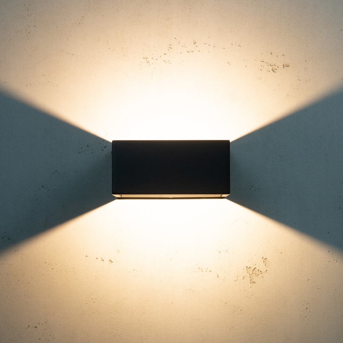 Jupiter Sort udendørslampe Fra Dyberg Larsen - Jupiter har en flad side mod væggen og en halvcirkelformet front med en LED lyskilde, der lyser op og ned langs væggen.