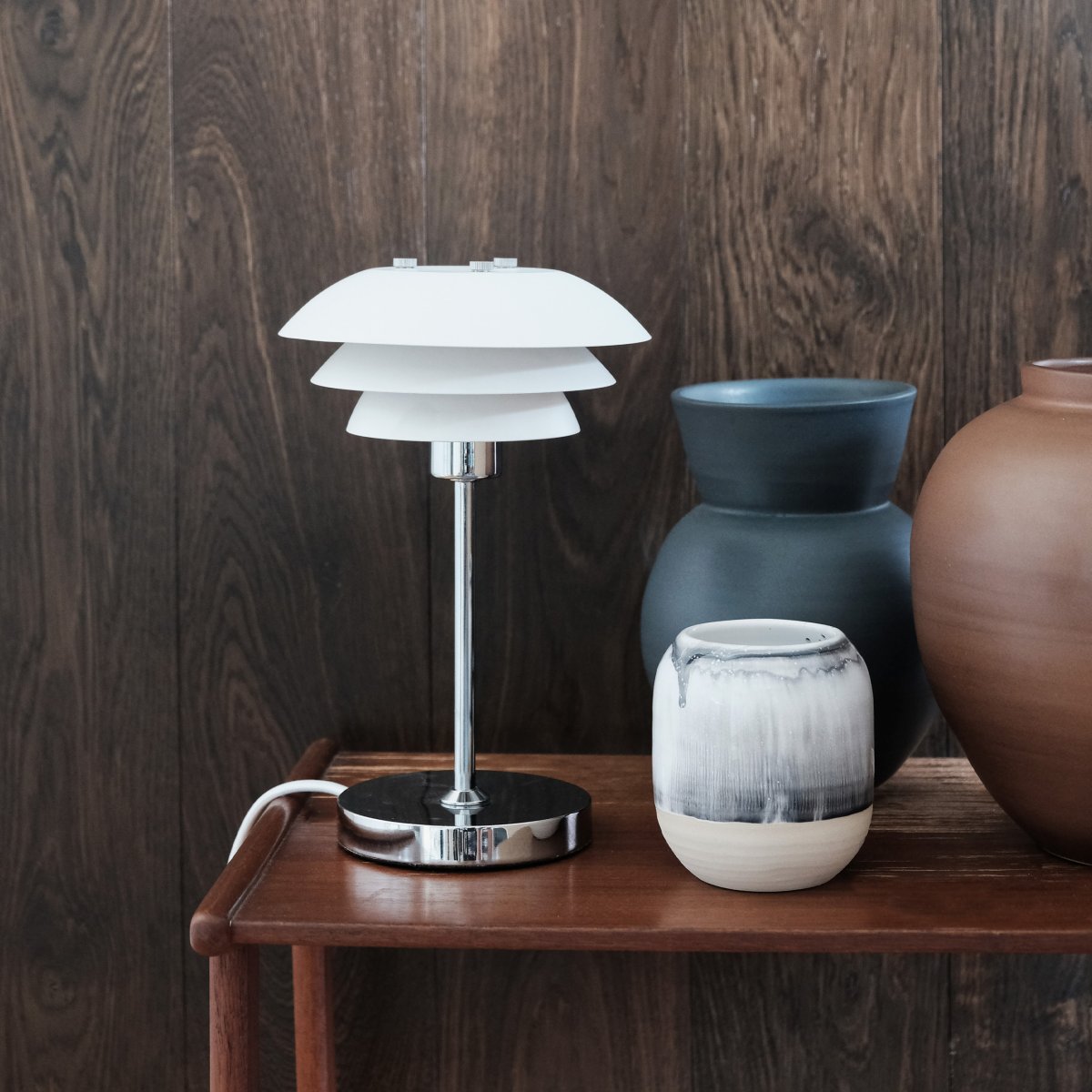 DL16 25cm Hvid bordlampe Fra Dyberg Larsen - Skærmene er lavet af metal og bunden i krom, med farvemulighederne sort og hvid.