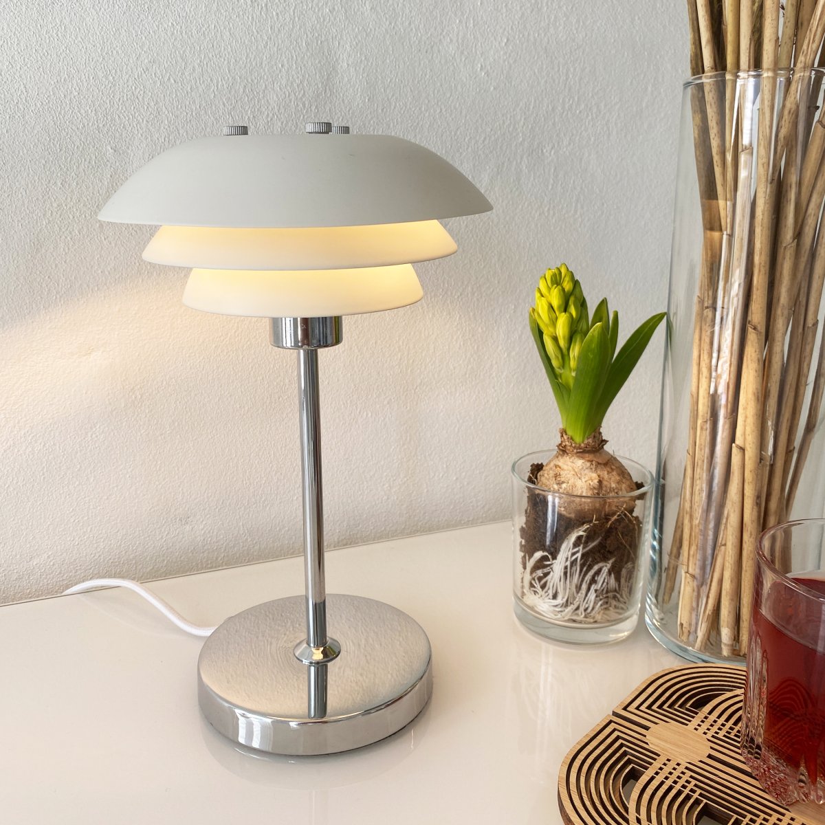 DL16 25cm Hvid bordlampe Fra Dyberg Larsen - Skærmene er lavet af metal og bunden i krom, med farvemulighederne sort og hvid.