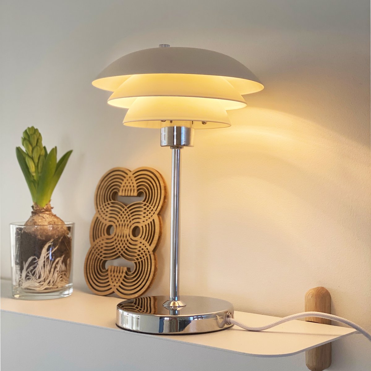 DL16 25cm Hvid bordlampe Fra Dyberg Larsen - Skærmene er lavet af metal og bunden i krom, med farvemulighederne sort og hvid.