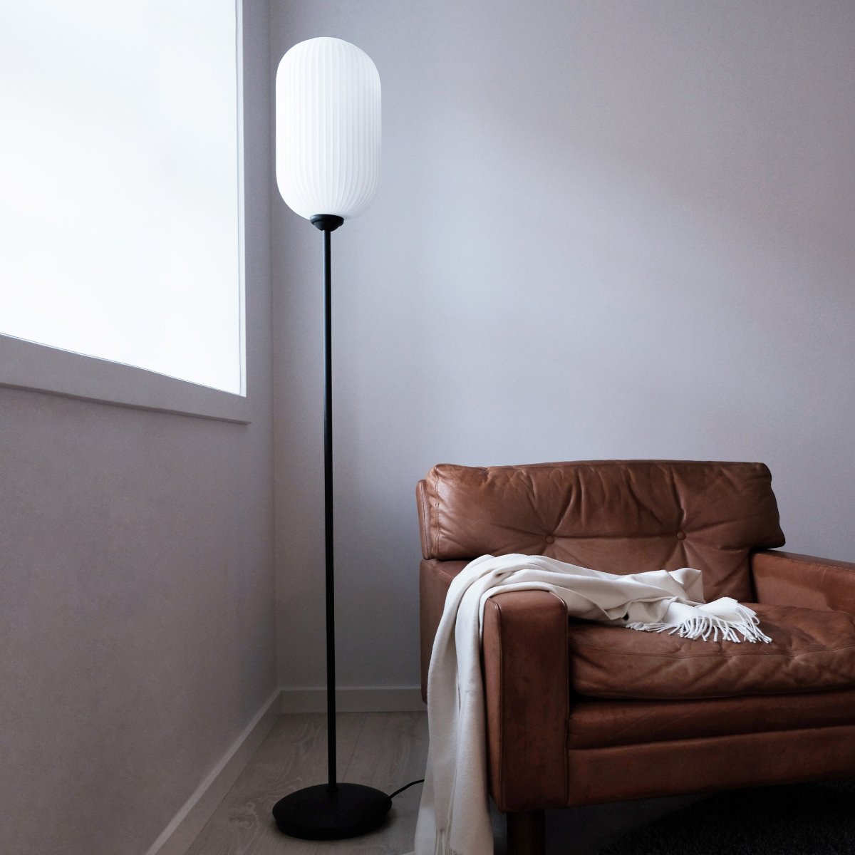 Riflet Sort gulvlampe Fra Dyberg Larsen - Riflet gulvlampen fra Dyberg Larsen har fået nyt design med en smukt ribbet lampeskærm i opalglas, der spreder et blødt og behageligt lys.