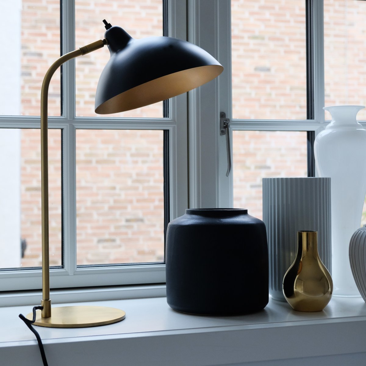 Futura 55cm Messing bordlampe Fra Dyberg Larsen - Den sorte overflade og den antikfarvede inderside af sk&aelig;rmen spreder et varmt lys og skaber en hyggelig atmosf&aelig;re i hjemmet.