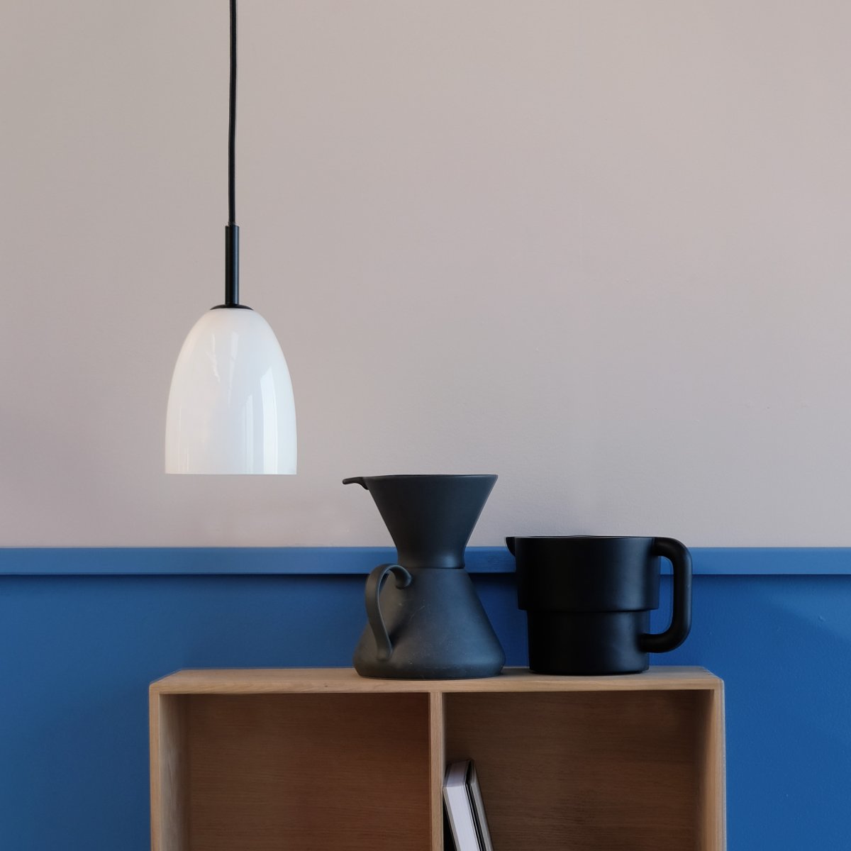 Jazz Ø12 Sort loftslampe Fra Dyberg Larsen - Jazz pendel i opal hvidt glas kombinerer en moderne glasskærm med minimalistisk sort ophæng, hvilket giver et sofistikeret touch til ethvert interiør.