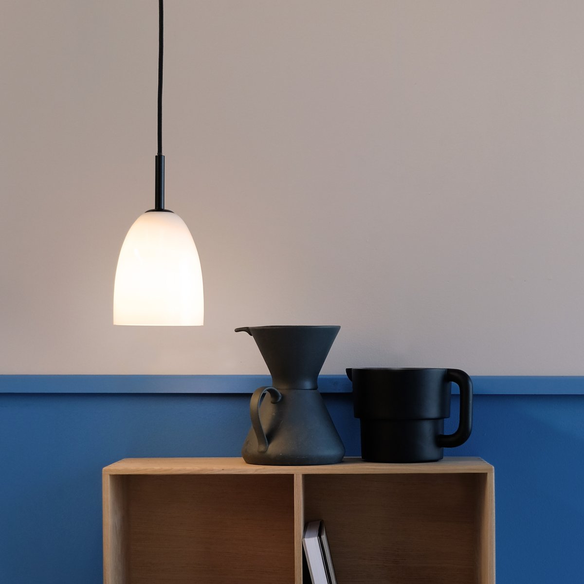 Jazz Ø12 Sort loftslampe Fra Dyberg Larsen - Jazz pendel i opal hvidt glas kombinerer en moderne glasskærm med minimalistisk sort ophæng, hvilket giver et sofistikeret touch til ethvert interiør.