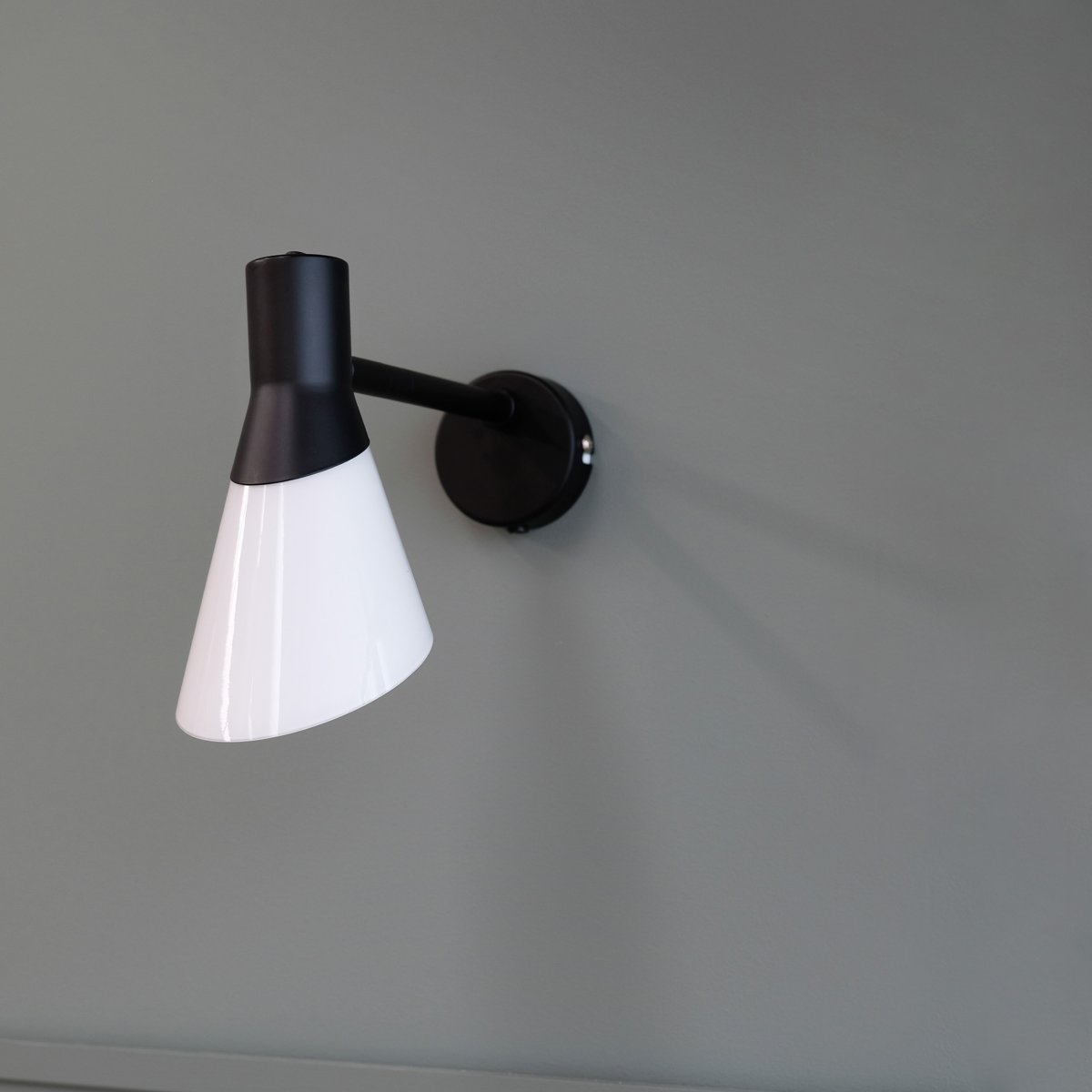 Gent 30cm Sort væglampe Fra Dyberg Larsen - Gent er en moderne og stilfuld væglampe med en lampeskærm af opalglas i kombination med sort metal.