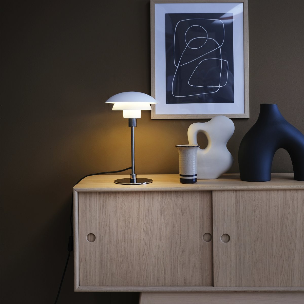 Morph 35cm Hvid bordlampe Fra Dyberg Larsen - Morph bordlampe i mat hvidt metal med kromfod skaber en klassisk og stilfuld nordisk atmosf&aelig;re.