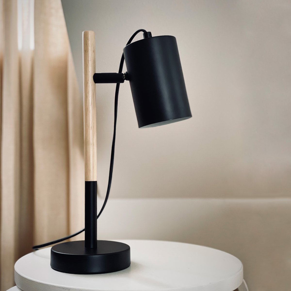 Woody 35cm Sort skrivebordslampe Fra Dyberg Larsen - Lampen har en sort metalskærm og fod, der giver et stilrent udtryk, mens benet er lavet af træ.
