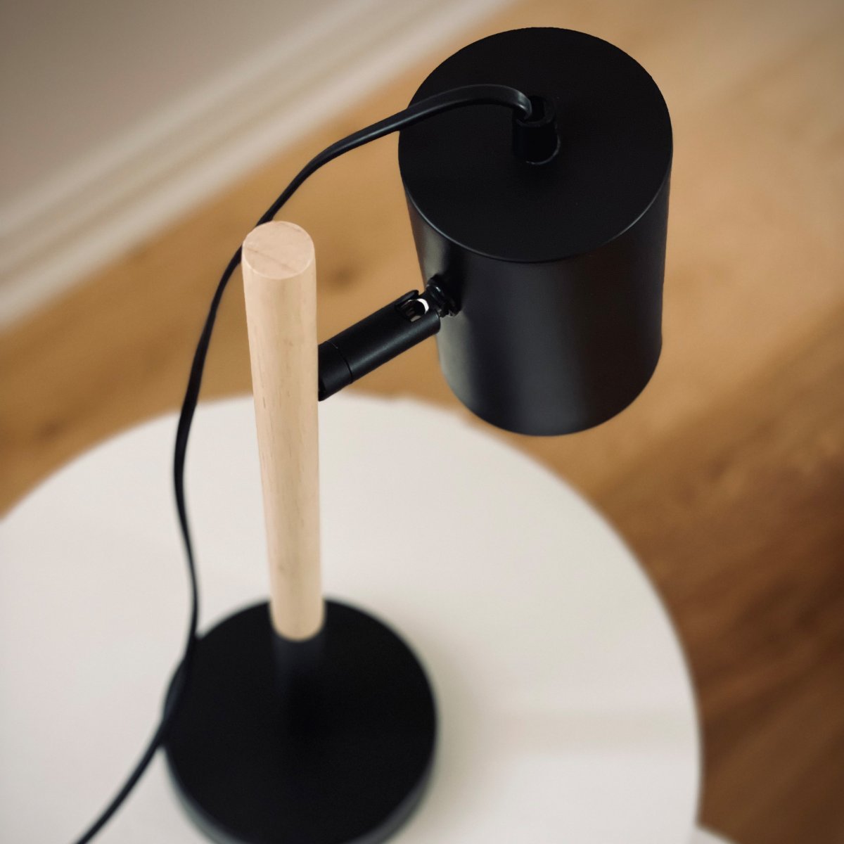 Woody 35cm Sort skrivebordslampe Fra Dyberg Larsen - Lampen har en sort metalskærm og fod, der giver et stilrent udtryk, mens benet er lavet af træ.