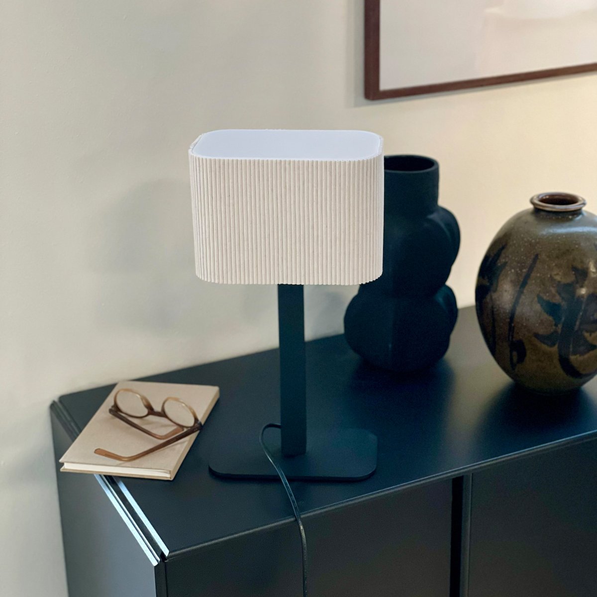 Calix oval 40cm Sort bordlampe Fra Dyberg Larsen - Den ribbade, naturf&auml;rgade sk&auml;rmen av textil medf&ouml;r en v&auml;rme till rummet och i kombination med den svarta metallfoten passar Calix in i alla stilar och hem.