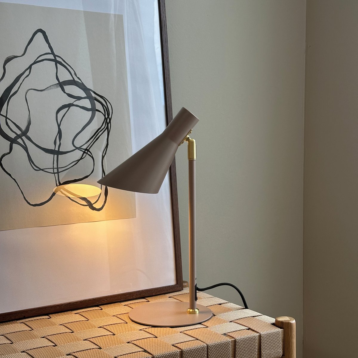 DL12 Mini 40cm Beige skrivebordslampe Fra Dyberg Larsen - Den er udstyret med en skærm, der både kan drejes og vippes, hvilket gør det nemt at styre lyset efter behov.