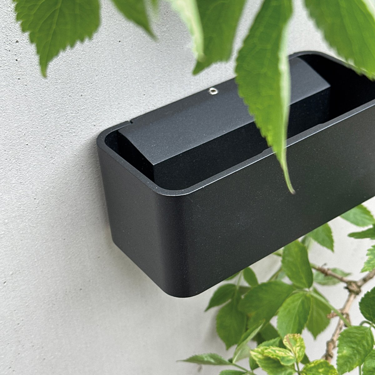 Saturn Sort udendørslampe Fra Dyberg Larsen - Med sit minimalistiske design og robuste konstruktion er den perfekt til udendørs brug og giver din facade et elegant løft.