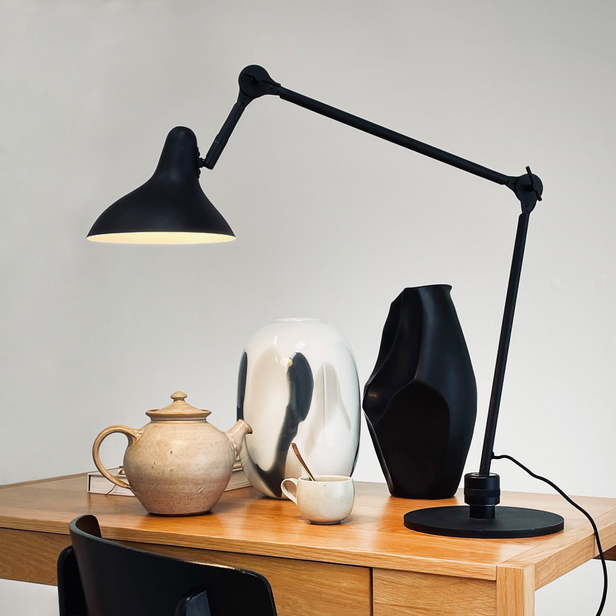 Lotus 85cm Sort skrivebordslampe Fra Dyberg Larsen - Med sin fleksible arm og justerbare skærm kan du nemt justere lyset efter behov, hvilket gør det perfekt til arbejdspladser eller klasseværelser.
