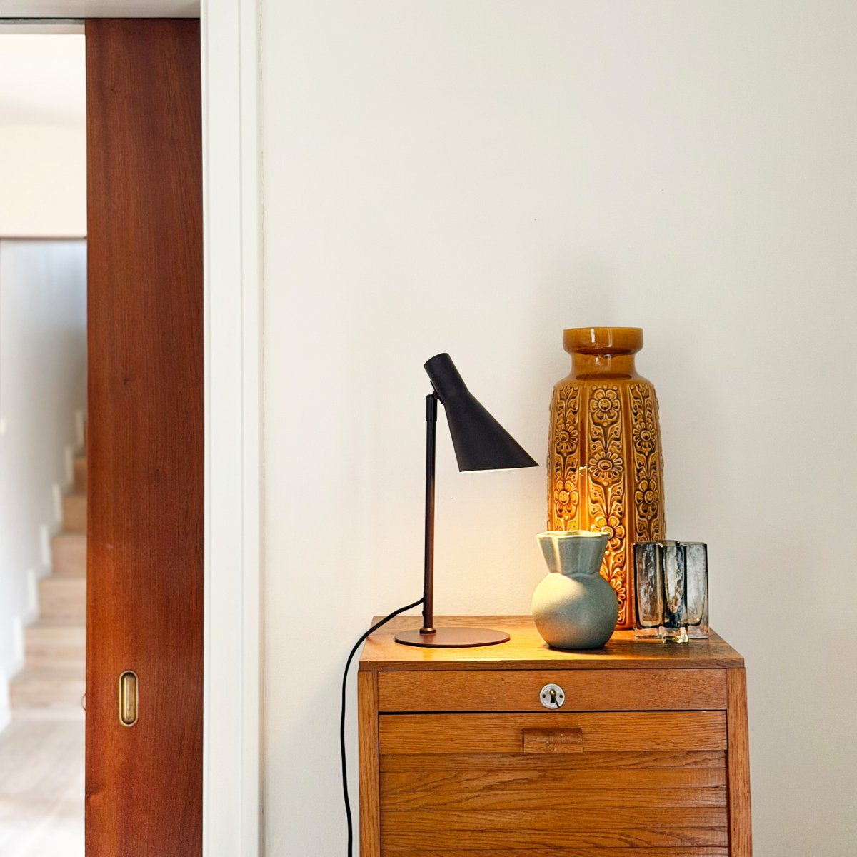 DL12 Mini 40cm Brun skrivebordslampe Fra Dyberg Larsen - Den er udstyret med en sk&aelig;rm, der b&aring;de kan drejes og vippes, hvilket g&oslash;r det nemt at styre lyset efter behov.