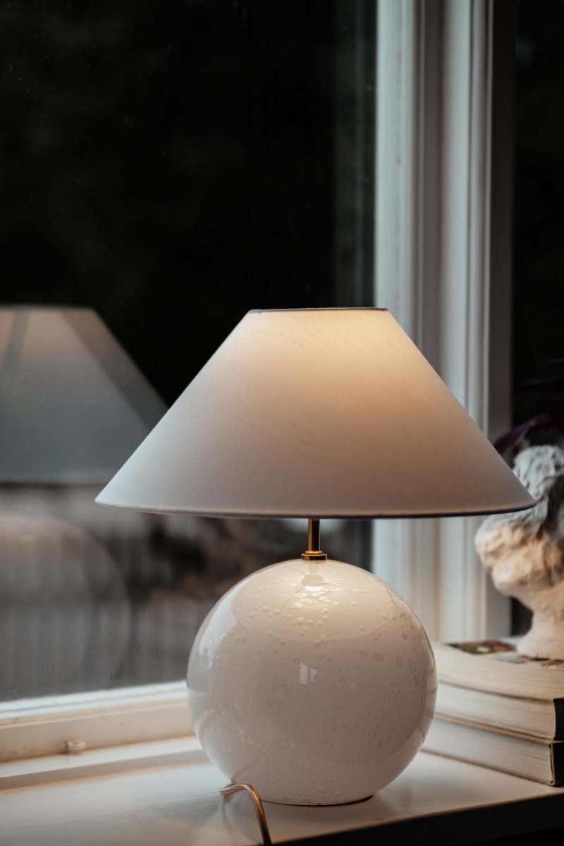 Iris 40cm Hvid bordlampe Fra Globen Lighting - Iris er en smuk bordlampe lavet af farvet glas med bl&aelig;ste luftbobler med en matchende bomuldssk&aelig;rm og en t&oslash;r top, der g&aring;r tone-i-tone med lampefoden.