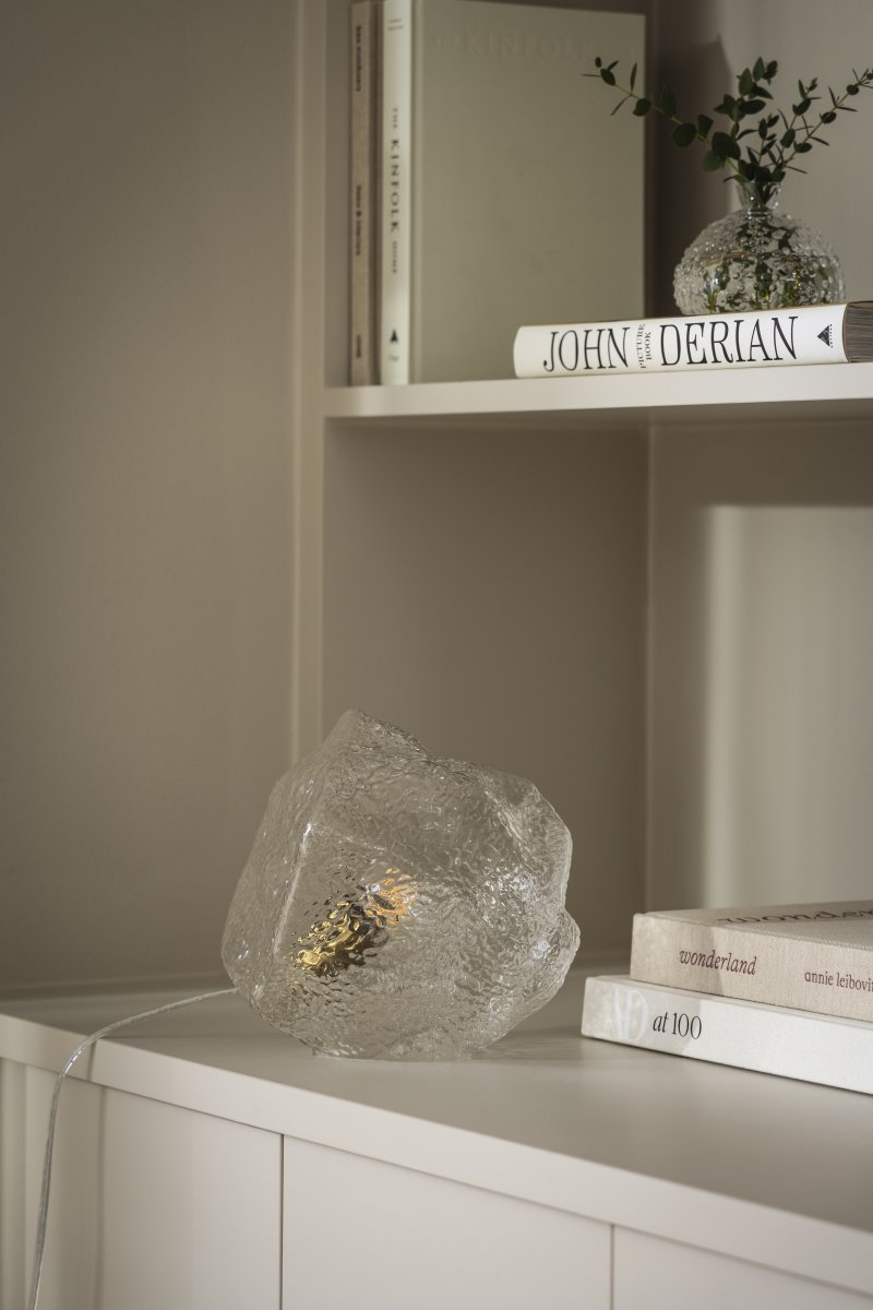 Valerie 22cm Gennemsigtig bordlampe Fra Globen Lighting - Det mundblæste glas med sin strukturerede overflade fanger lyset og skaber et levende lysspil.