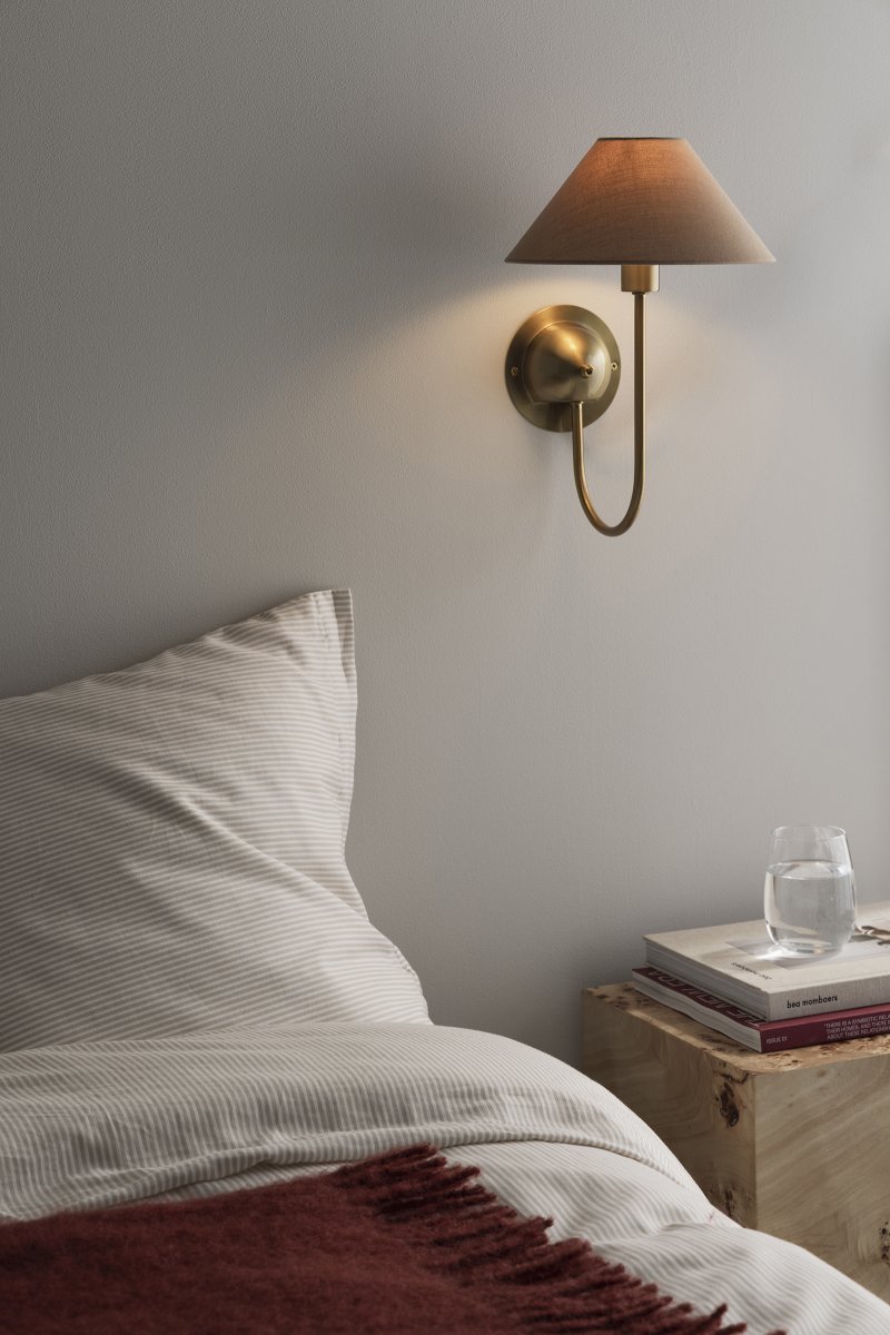 Iris 32cm Messing/brun væglampe Fra Globen Lighting - Den blødt buede arm er kombineret med en brun tekstilskærm, der skaber et varmt og klassisk udtryk.