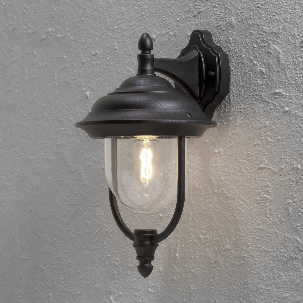 Parma Sort udendørslampe Fra Konstsmide - Med sin smukke form og klare glaskuppel spreder den et varmt og imødekommende lys, ideelt til entre og terrasser.