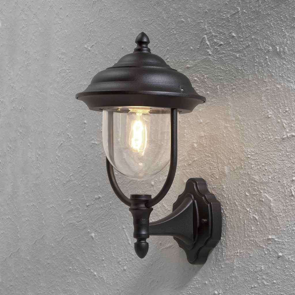 Parma Sort udendørslampe Fra Konstsmide - Med sin smukke form og klare glaskuppel spreder den et varmt og imødekommende lys, ideelt til entre og terrasser.