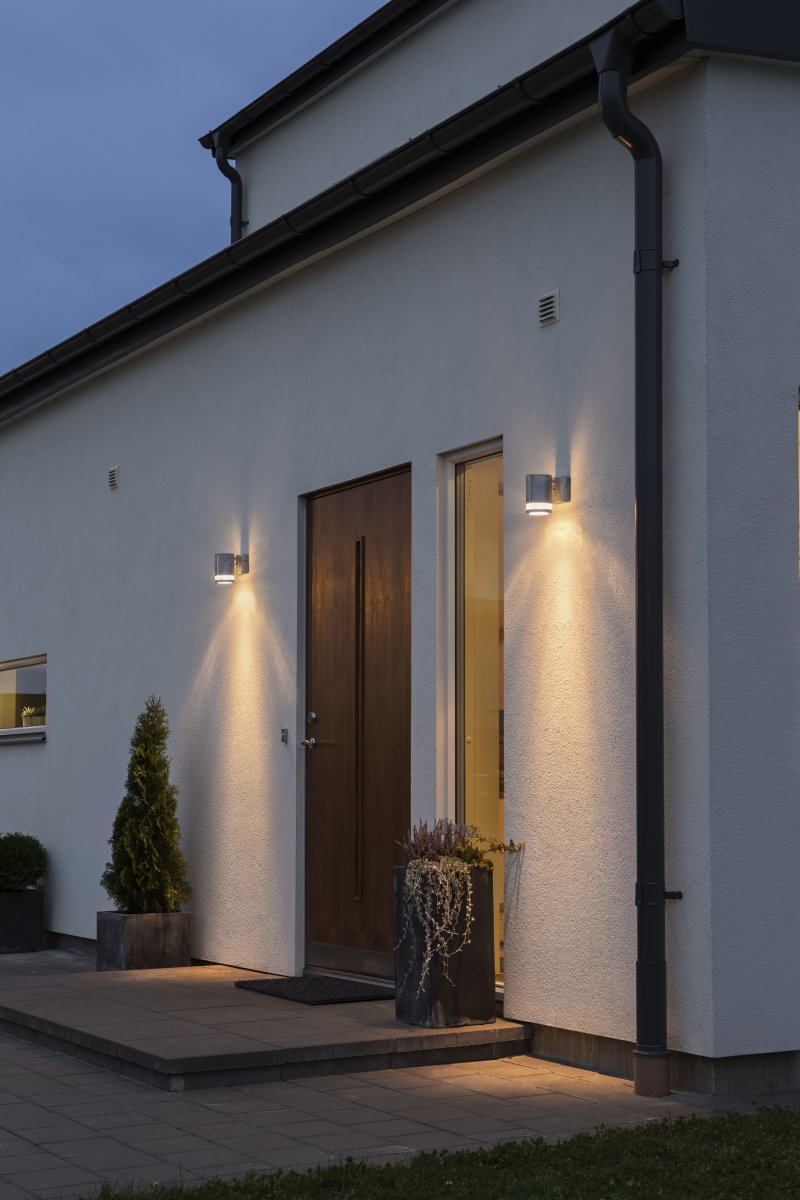 Modena Galvaniseret udendørslampe Fra Konstsmide - Modena er en stilfuld facadelampe fremstillet af galvaniseret metalplade med en elegant detalje i transparent akrylglas, der giver lampen et moderne udtryk.